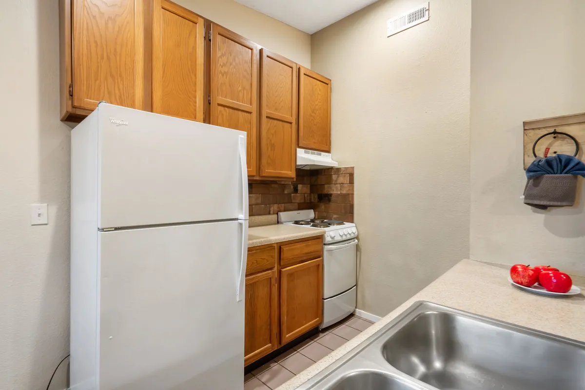 A cozy, well-lit kitchen with modern appliances including a refrigerator, stove, and ample cabinetry. The scene invites viewers to imagine meal preparation and family gatherings, highlighting the practicality and warmth of the culinary space.