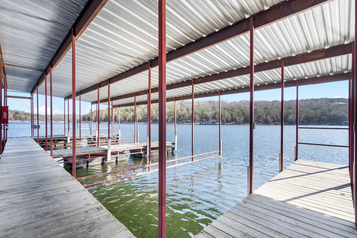 A serene lakeside scene featuring a wooden dock extending over calm water, bordered by a tree-lined shore. Early morning light creates a tranquil atmosphere, perfect for peaceful moments. The dock invites quiet reflection or a shared cup of coffee while listening to the gentle sounds of nature.