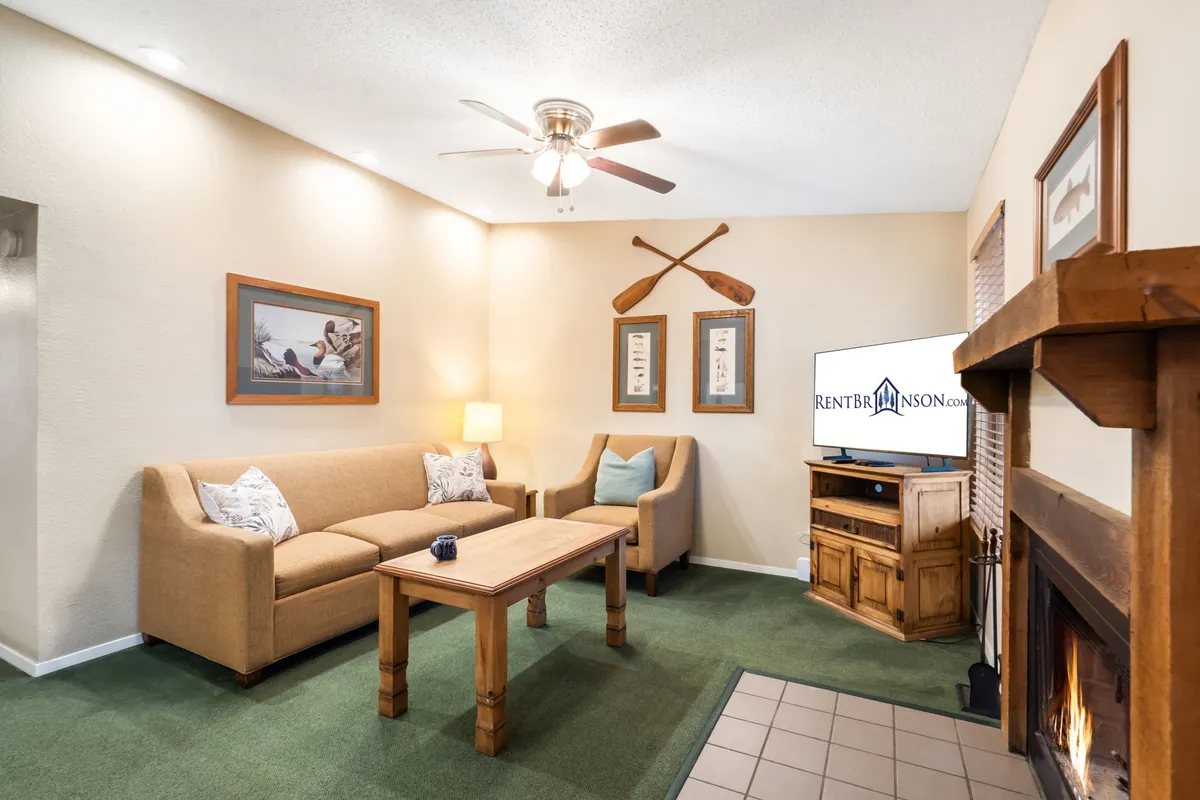 A comfortable living room area with a soft sofa, coffee table, fireplace, and decorative oars on the wall. The setting is ideal for relaxing, socializing, or enjoying a cozy evening indoors.