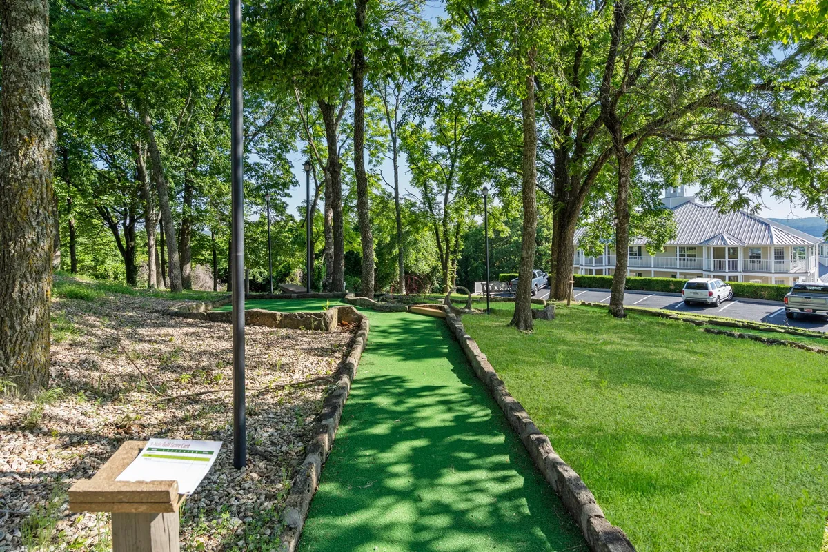 A playful mini-golf course winding through trees and green spaces, with clear signage and inviting paths. The setting promises friendly competition and lighthearted moments amid the resort’s natural surroundings.